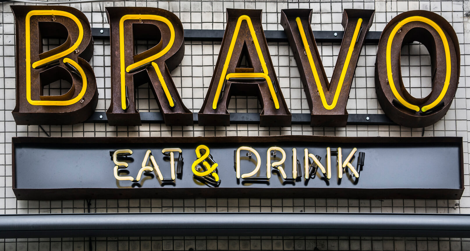 neon-bravo-eat-drink-neon-nad-wejsciem-do-restauracji-neon-na-kaflach-neon-na-scianie-z-kafli-neon-podswietlany-neon-wewnatrz-blachy-nierdzewnej-neon-na-zewnatrz-zolty-neon-warszawa-centralna